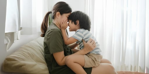 boy sitting on mother lap having fun