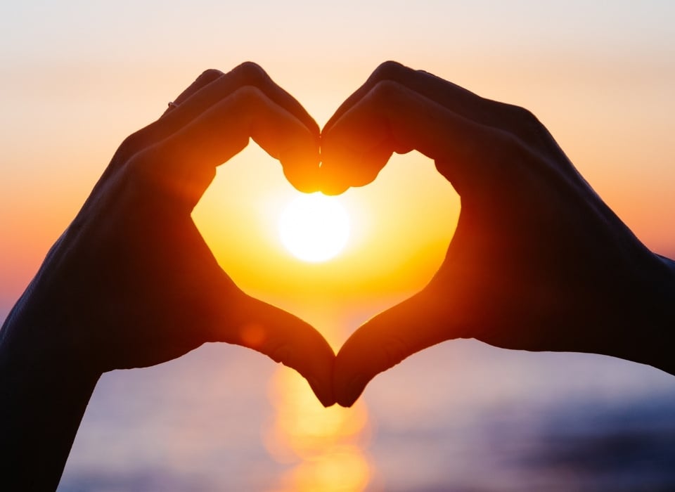 couple-hands-forming-a-heart-shape-with-sunset