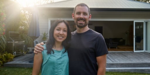 happy couple with home in background