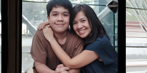 mother cuddling son & looking forward