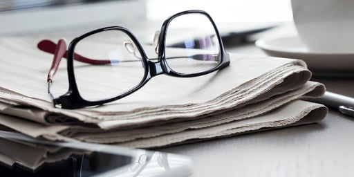 newspaper and reading glasses on table