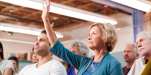 senior woman asking question by raising hand in auditorium