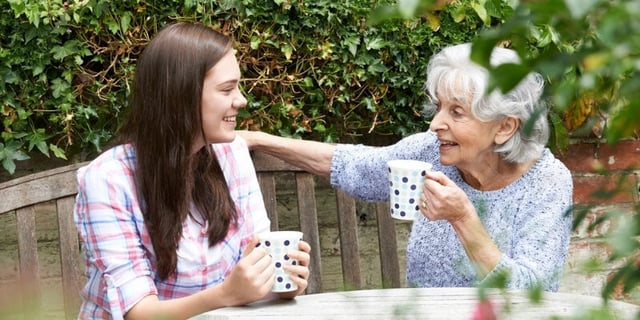 volunteer with elderly women sipping coffee
