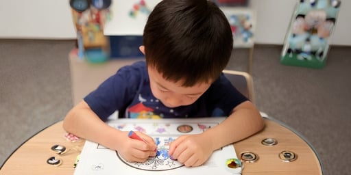 young kid coloring in room