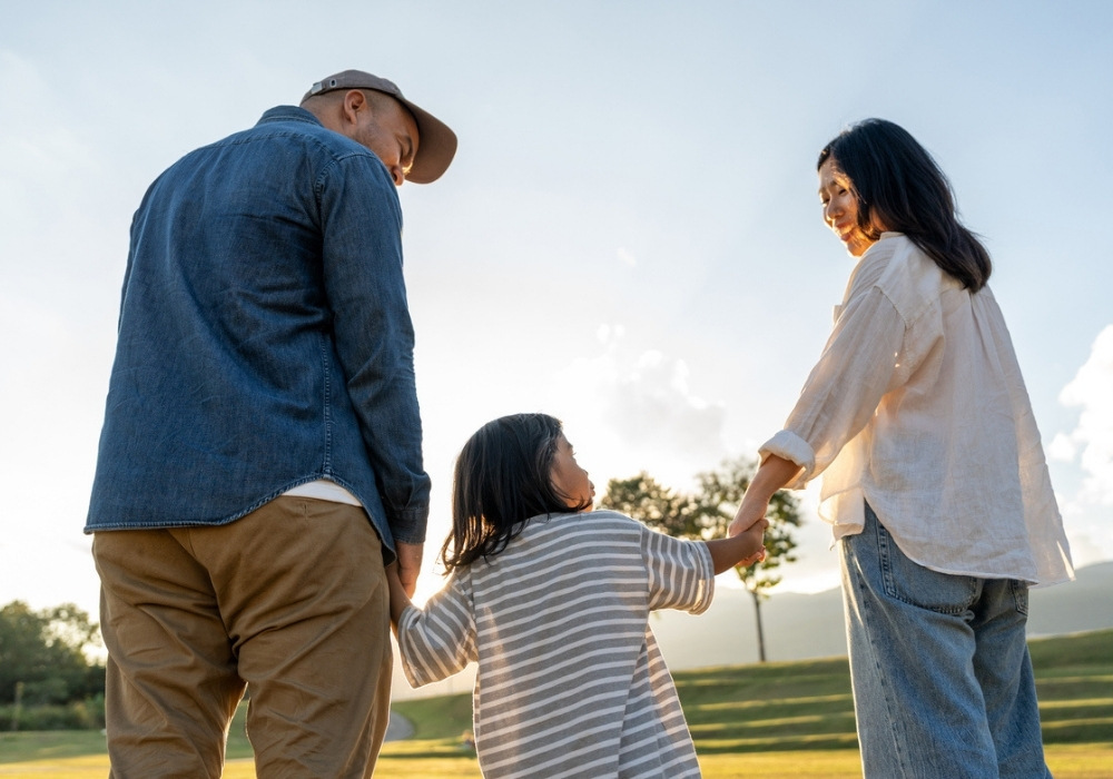 father & mother with kid in open field