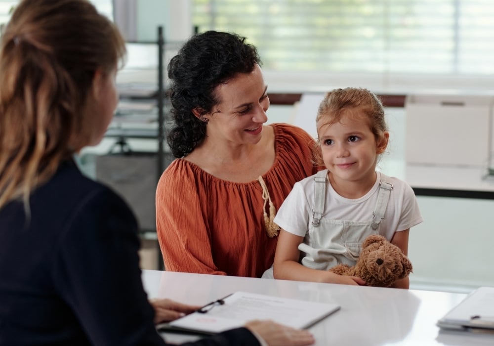 mother with young girl in lap talking to a counsellor